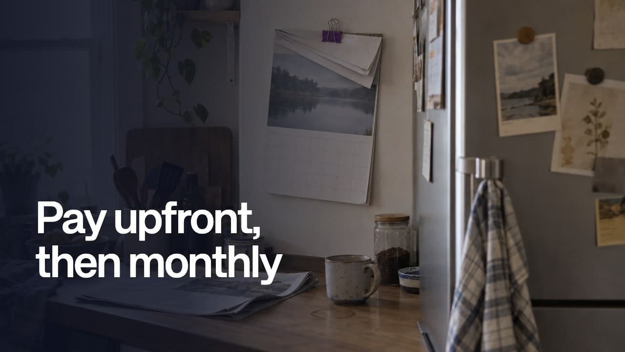 Pay upfront, then monthly, over a kitchen with a clipped wall calendar, a newspaper and a coffee mug